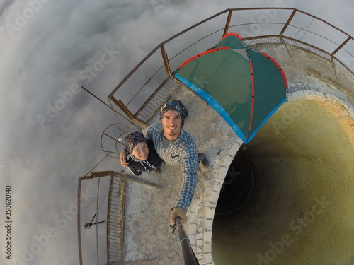 Camping on top of a smoke stack chimney, surrounded by fog and mist underneath the top of the building, sunrise