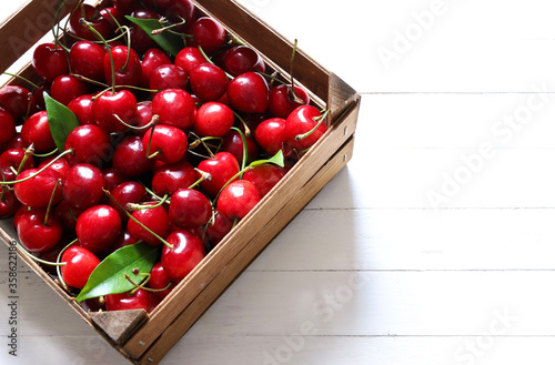 Concetto di frutta estiva. Ciliegie deliziose fresche in una scatola di legno su fondo bianco. Vista dall'alto. photo