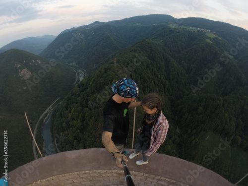 Taking an extreme selfie on top of a ruined tower, life risking extreme sports, happy couple enjoying the panorama 