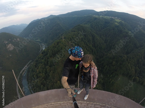 Taking an extreme selfie on top of a ruined tower, life risking extreme sports, happy couple enjoying the panorama 
