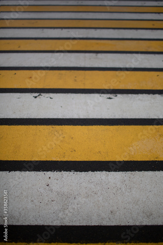 Pedestrian crosswalk-alternating white and yellow stripes on the asphalt for the safety of pedestrians on the roads © Ekaterina