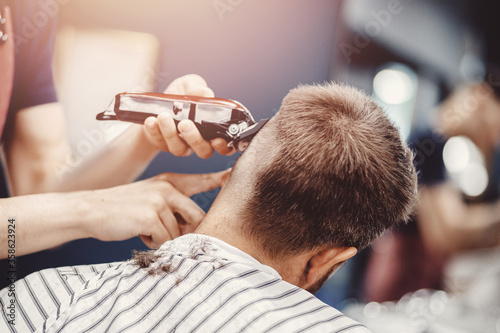 Hairdresser cuts hair men in barbershop. Barber doing correct trim electric shaver