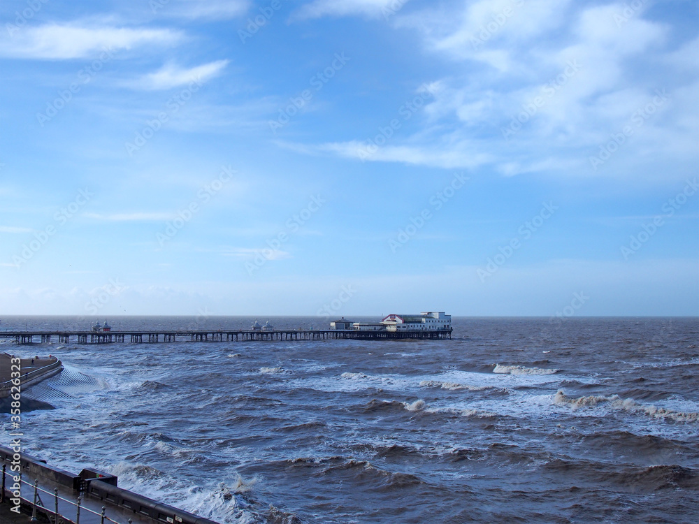 view of the south pier it blackpool with the sea a full tide in front of the promenade and a blue sunlit sky