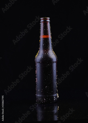 Bottle of beer shot on black surface,with black background.