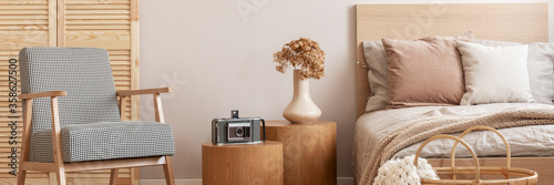 Retro armchair, wooden bedside tables and bed in a cozy bedroom interior photo