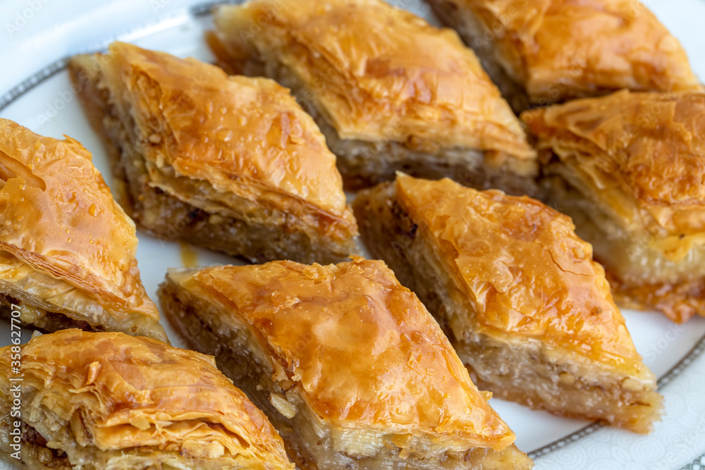 Turkish national delight baklava with walnuts and honey on a white wooden background. Traditional eastern dessert. Turkish national delight baklava with walnuts and honey on a white wooden background. Traditional eastern dessert.