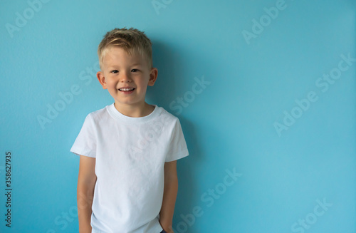 portrait of a happy little boy smiling on blue background. 