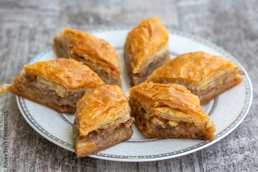 Turkish national delight baklava with walnuts and honey on a white wooden background. Traditional eastern dessert. Turkish national delight baklava with walnuts and honey on a white wooden background. Traditional eastern dessert.