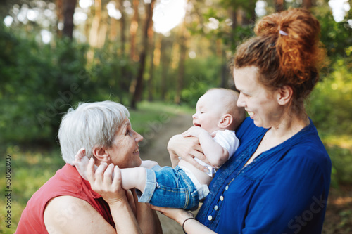 Mom, Grandmother and baby walking in the summer forest.