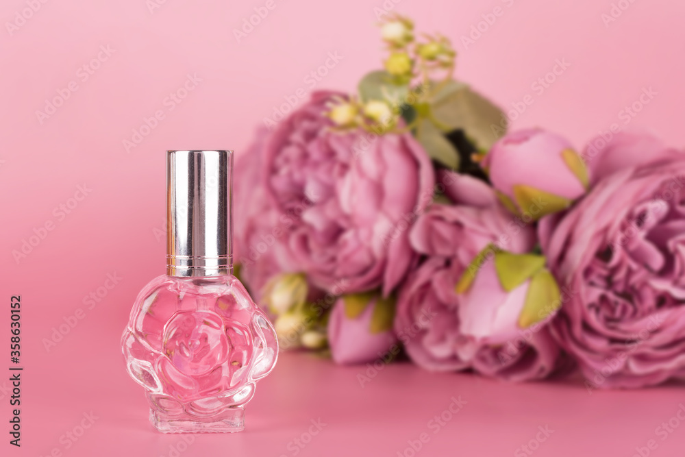 Transparent perfume bottle with bouquet of peonies on pink background. Aromatic essence bottle with spring flowers. Perfumery, cosmetics, fragrance collection. Transparent perfume bottle with bouquet of peonies on pink background. Aromatic essence bottle with spring flowers. Perfumery, cosmetics, fragrance collection.