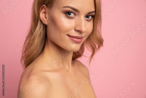 Portrait of pretty charming cute girl with plump lips looking at camera having perfect skin isolated on pink background, advertisement concept. copy space
