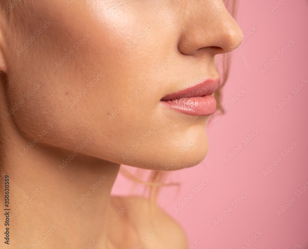 Obraz premium Close Up half face portrait of attractive, nude girl with soft, healthy plump lips isolated on pink background, with copy space, health, healthcare, advertisement concept