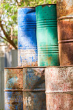 Colorful of broken rusty oil barrels placed stacking with other in junk yard