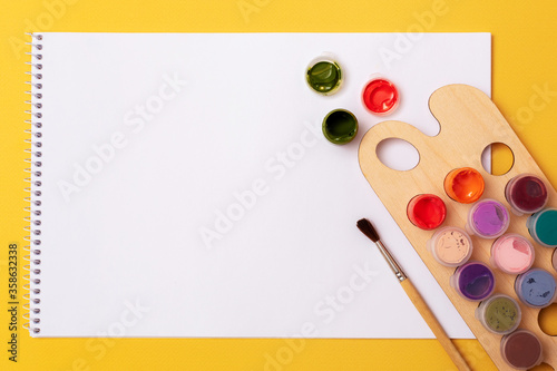 Paints, brushes, album. On yellow background. Accessories for the artist.
