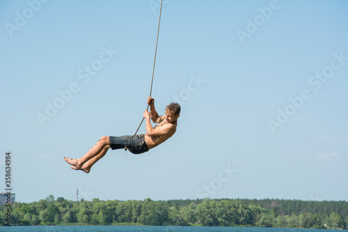 In the summer, on a bright sunny day, children ride a bungee on the lake. © tsomka