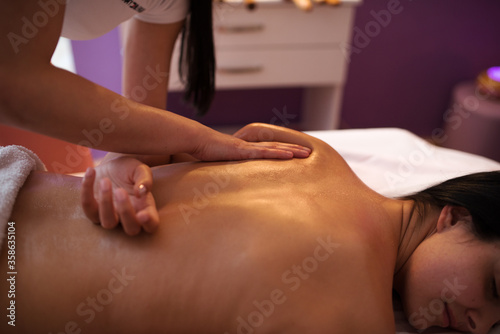 Young woman receiving massage in spa salon.