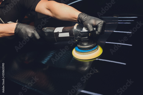 Car detailing - Hands with orbital polisher in auto repair shop. Selective focus. photo