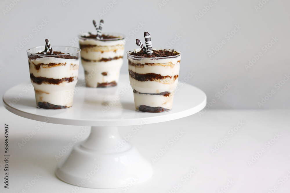 Classic tiramisu dessert in a glass and cup of coffee on light background. dessert with copy space closeup Classic tiramisu dessert in a glass and cup of coffee on light background. dessert with copy space closeup