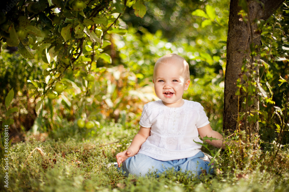 baby girl sitting on grass in garden under small Apple tree. gardening. baby girl sitting on grass in garden under small Apple tree. gardening.