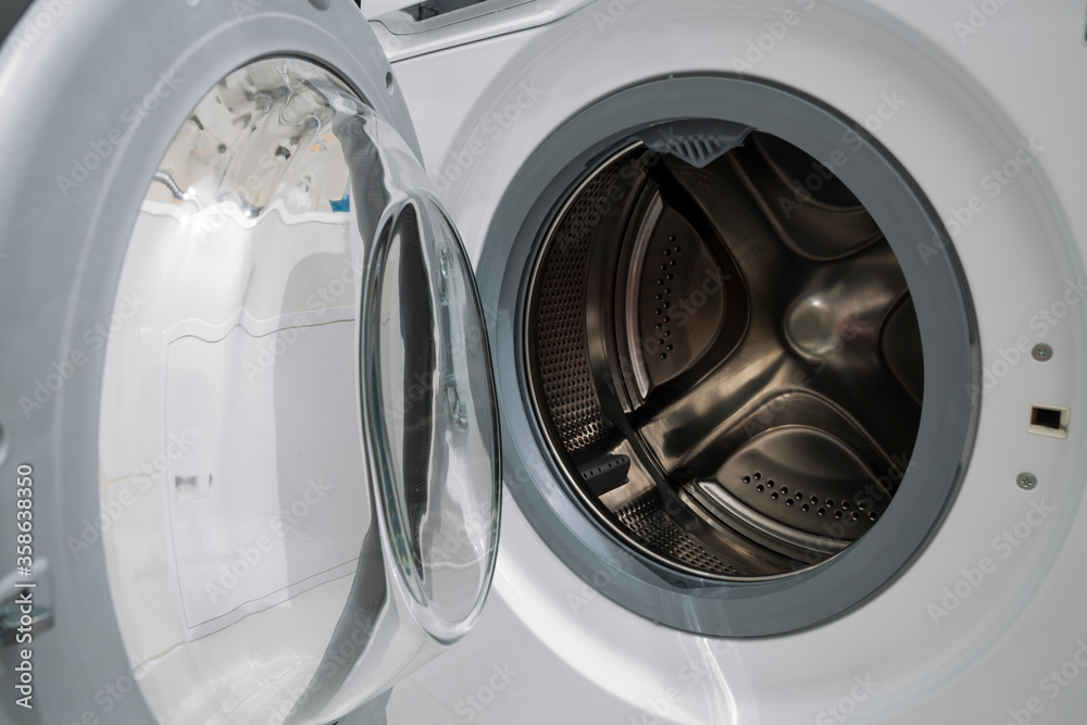 Household machine for washing fabric laundry with an open lid for loading in a household sanitary, technical room.