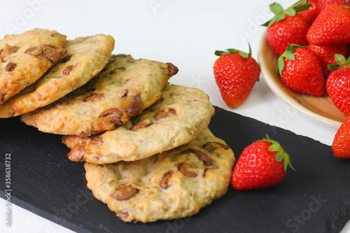 cookie with chocolate on slate plate and strawberry on light background. dessert concept