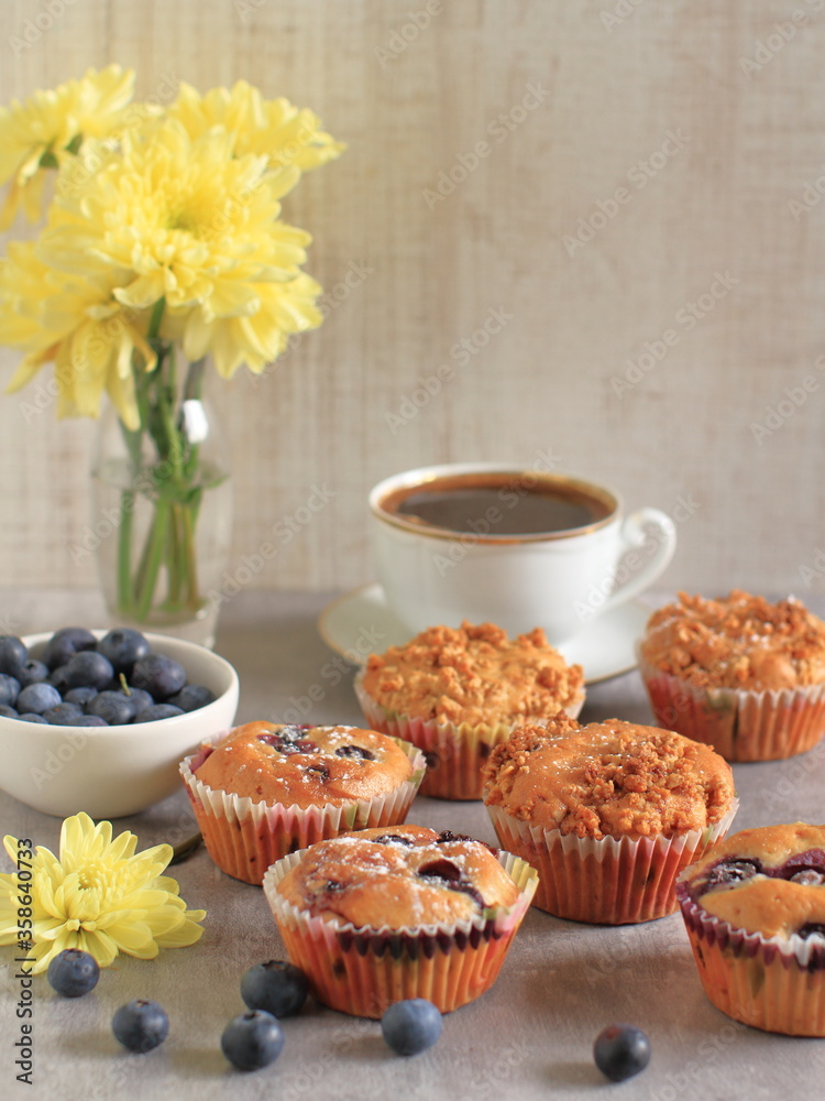 Blueberry muffins on a rustic wooden table and a cup of coffee
