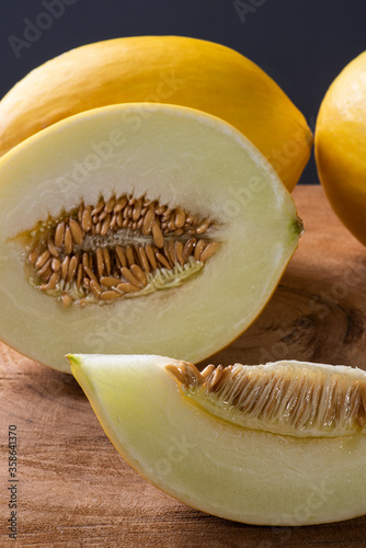 Whole and sliced ​​yellow melon on wooden background