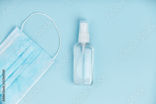 Hand sanitizer with medical mask on blue background.