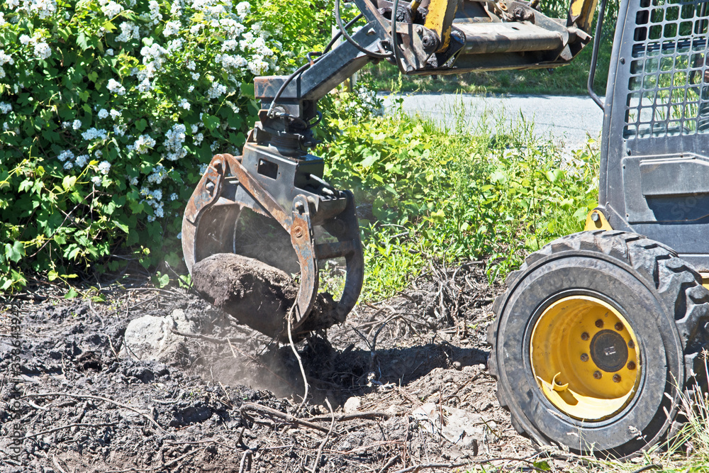 Fototapeta premium An excavator moves a large rock from the ground.