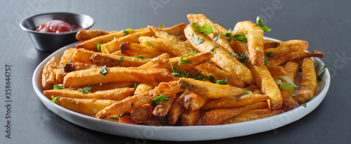 Fotografia plate of crispy seasoned french fries with parsley garnish