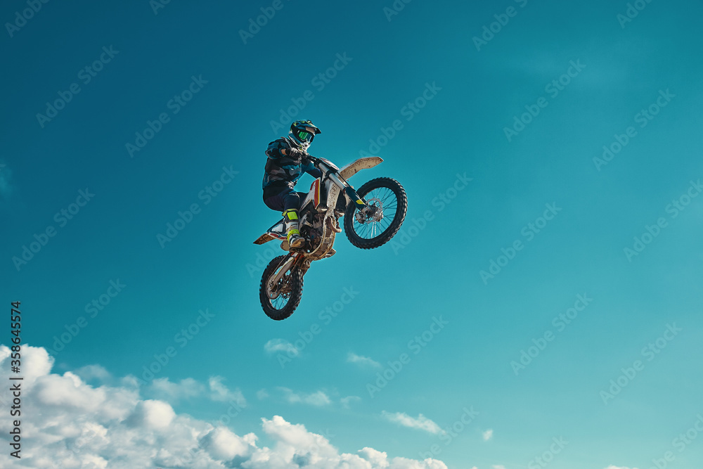 Extreme concept, challenge yourself. Extreme jump on a motorcycle on a background of blue sky with clouds. Copy space, all or nothing. Extreme concept, challenge yourself. Extreme jump on a motorcycle on a background of blue sky with clouds. Copy space, all or nothing.