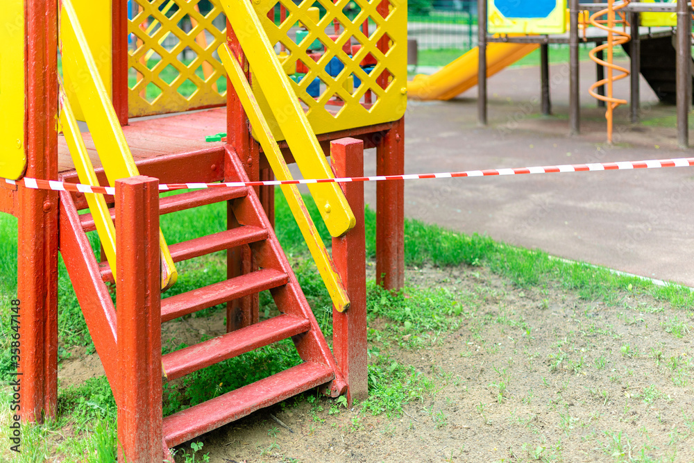 A yellow slide for children's entertainment in the park is wrapped with red barrier tape. Outside. Prohibition of outdoor walks, prevention of the coronavirus influenza virus covid-19. bacterium. A yellow slide for children's entertainment in the park is wrapped with red barrier tape. Outside. Prohibition of outdoor walks, prevention of the coronavirus influenza virus covid-19. bacterium.