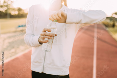 athletic woman holds a water bottle while standing outdoors in a stadium
