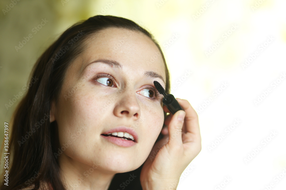 Young white brunette girl paints eyes and eyebrows with makeup Young white brunette girl paints eyes and eyebrows with makeup