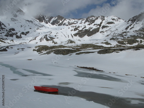 Snowy mountains landscape with red boat in the Stelvio National Park, Italy photo