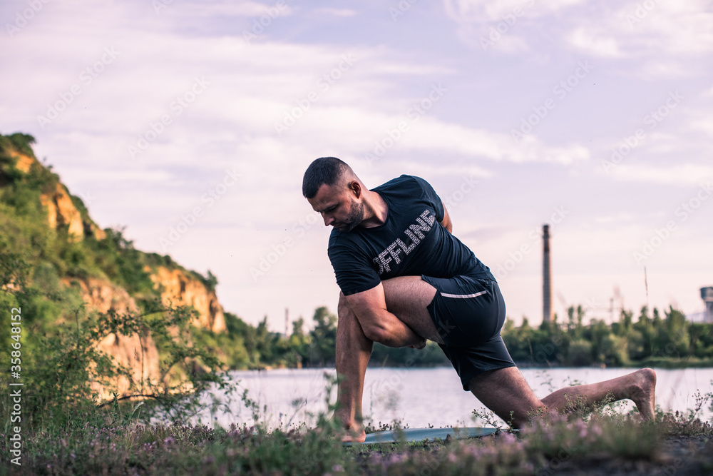 Obraz premium A young man doing yoga in nature. Healthy lifestyle, meditation, lifestyle concept. International Day of Yoga
