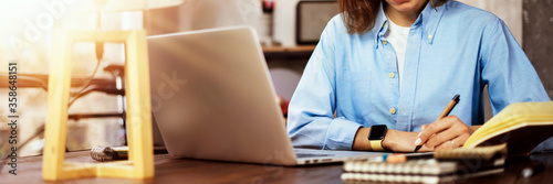 Young woman working with a laptop. Female freelancer connecting to internet via computer. Blogger or journalist writing new article. photo