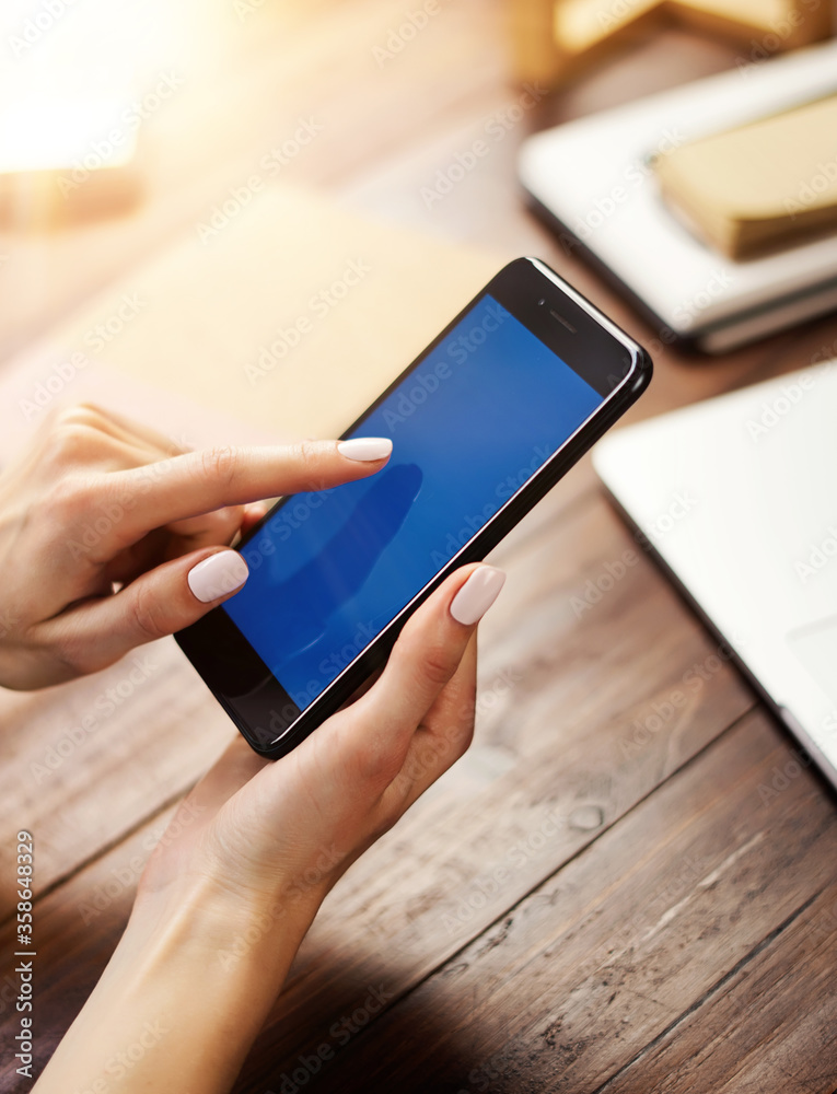 © Rymden - Mockup image of a woman using smartphone with blank screen on wooden table © Rymden - Mockup image of a woman using smartphone with blank screen on wooden table
