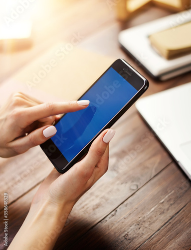 Mockup image of a woman using smartphone with blank screen on wooden table