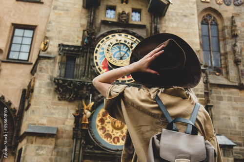 Blonde girl with hat and backback near famous clock in Prague, Czech Republic photo