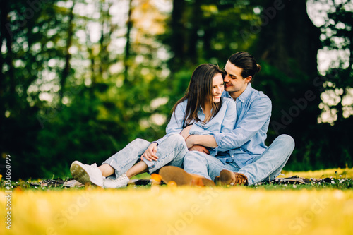 Young in loved couple sitting on the grass in a summer garden