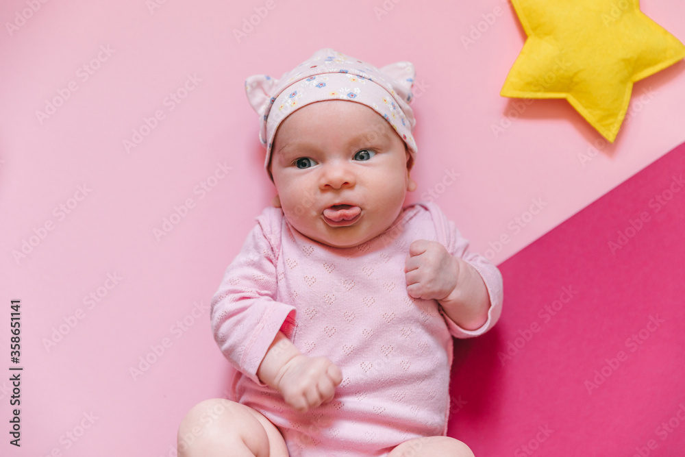 Cute baby on a pink background with toys and baby accessories Cute baby on a pink background with toys and baby accessories