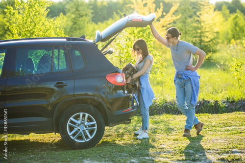 Young man open the trunk of his hired car girlfriend get some stuff on trip on sunset. Couple with car in trip © F8  \ Suport Ukraine