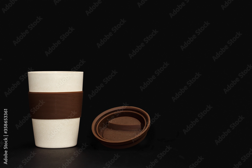 A cup of bamboo, environmentally friendly, on a black background. A cup of light shade with a brown lid. A cup of bamboo, environmentally friendly, on a black background. A cup of light shade with a brown lid.