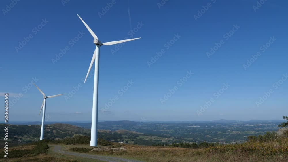 View of a wind turbines with huge propeller on a top of a hill