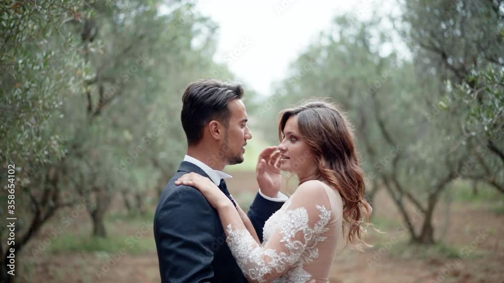 Young married couple enjoying the presence of each other in the garden, amazing cinematic frame of newlyweds with intimate kisses and hugs. Affection from the first sight, beginning of new family Young married couple enjoying the presence of each other in the garden, amazing cinematic frame of newlyweds with intimate kisses and hugs. Affection from the first sight, beginning of new family