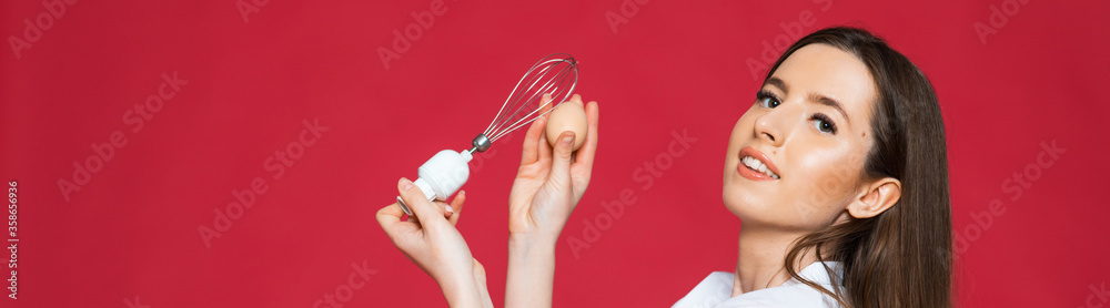 Image of screaming excited positive young woman chef holding whisk and eggs isolated over pink wall background.