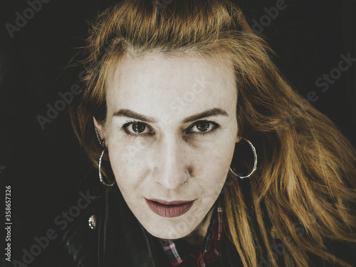 Beautiful girl with round earrings cheekily looks at the photographer photo