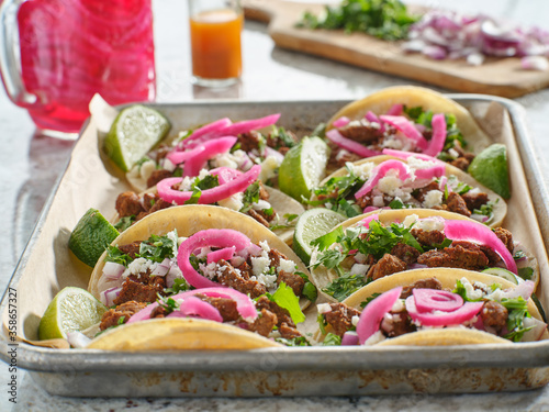 tray of carne asada tacos topped with pickled onions and cojita cheese photo