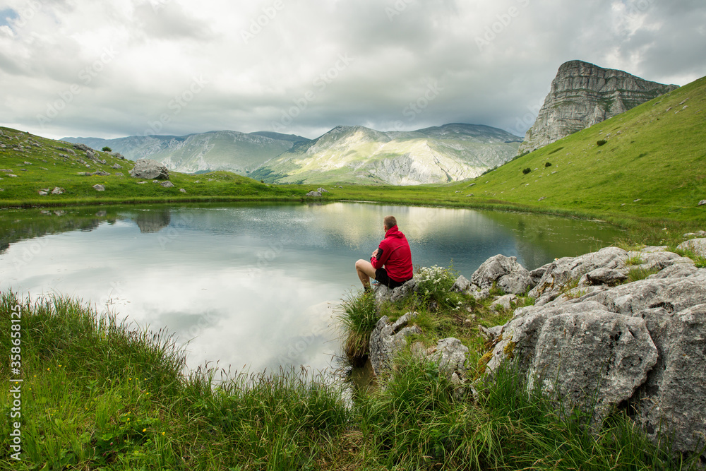 Hiker standing near mountain lake